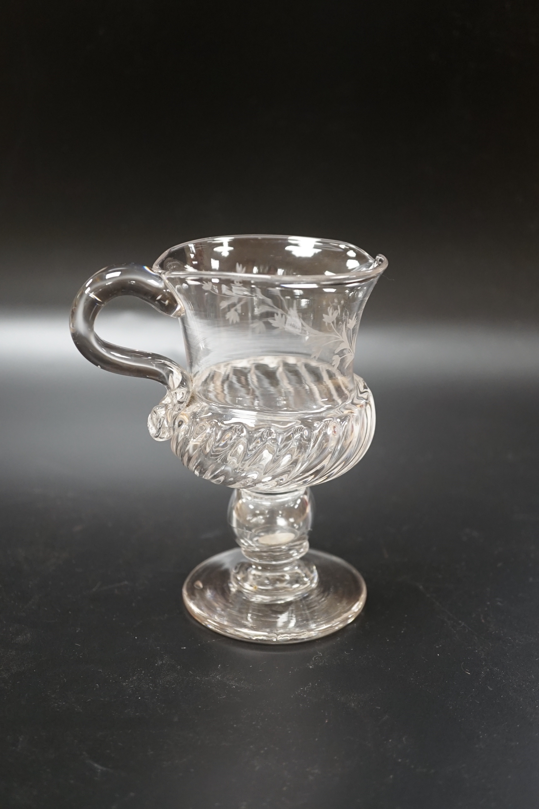 A Georgian glass jug on a stem, knop containing loose Charles II coin and engraved foliage with a central ‘SB’, 13.8cm